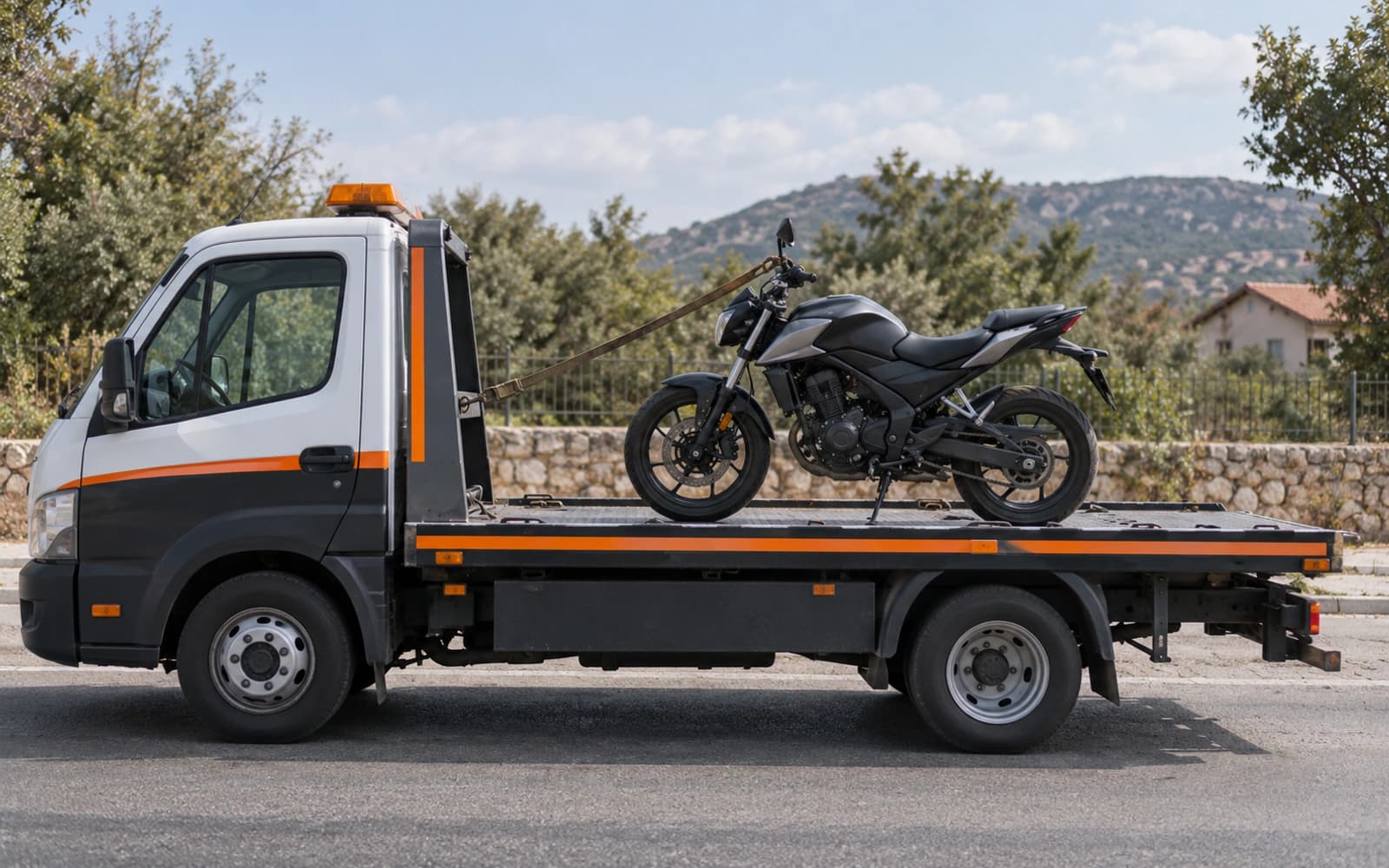 Kayar kasa üzerinde yan standında duran motosiklet; yalnızca gidon aynasına takılmış tek bir kayış var, ön tekerlek serbest